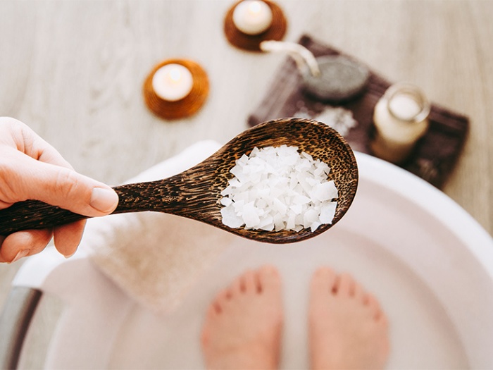 magnesium bath woman holding a spoon full of magnesium flakes feet bath