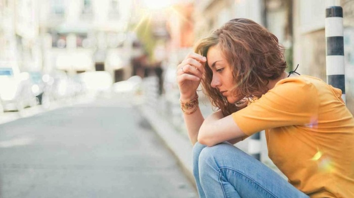 magnesium deficiency woman in a low mood sitting on the pavement on the street