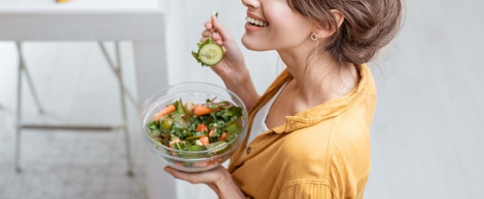 magnesium supplement woman smiling and eating a salad with a fork