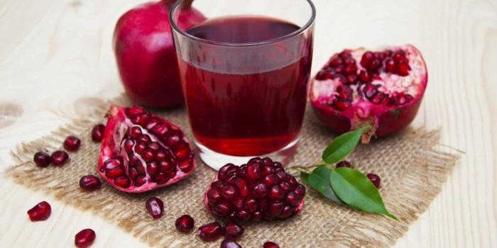 pomegranate juice in a glass with broken pomegranates around 