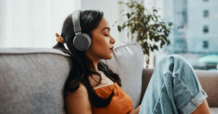 sound therapy relaxation technique woman with her earphones sitting on a couch listening to music