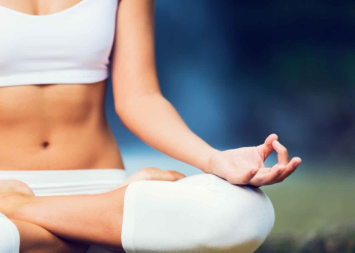 stress relief woman in a yoga pose with her legs crossed and her hands in a mudra