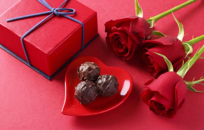 valentine day red wrapped gift chocolate candy in a heart shape plate and three red roses