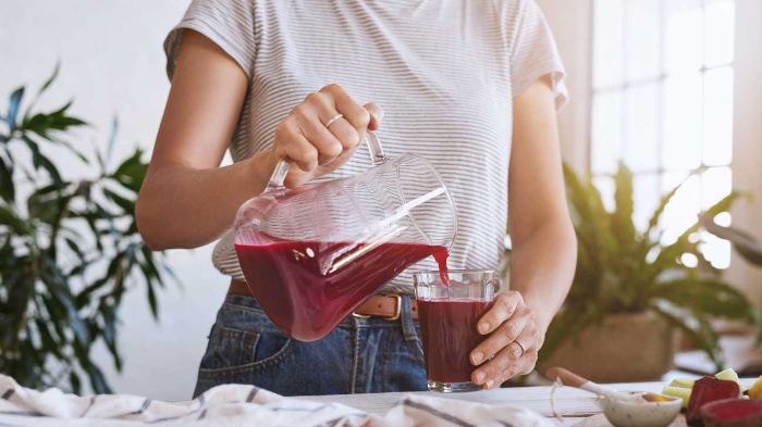 vegetable juice woman pouring red juice from a jug to a glass over a table