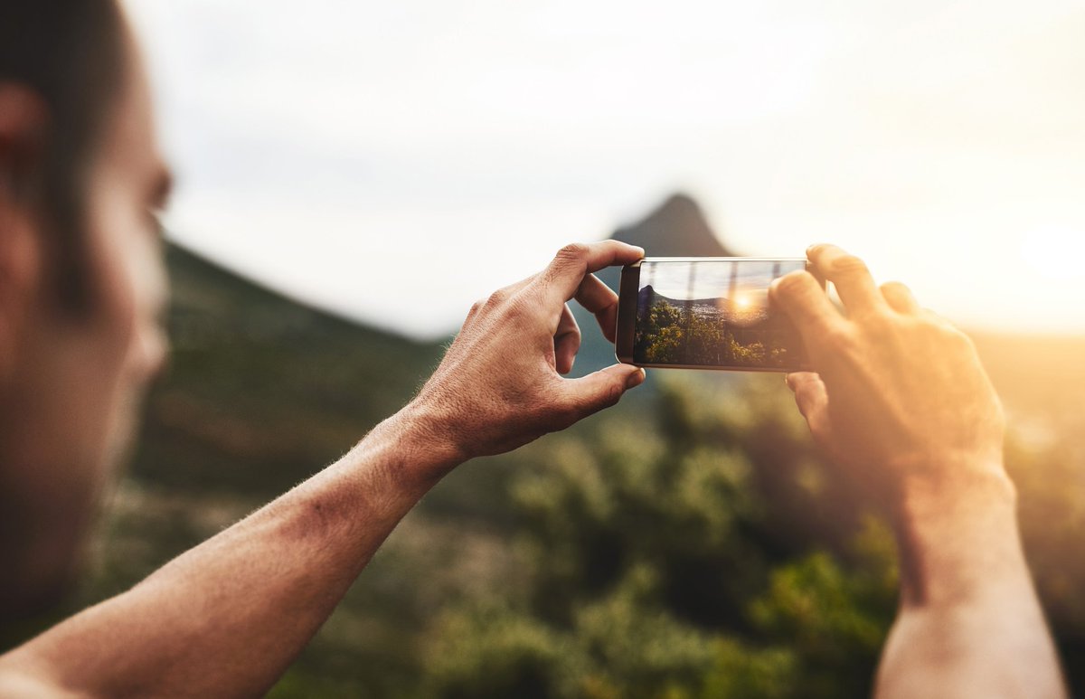 man taking outdoor photos with his phone zooming in