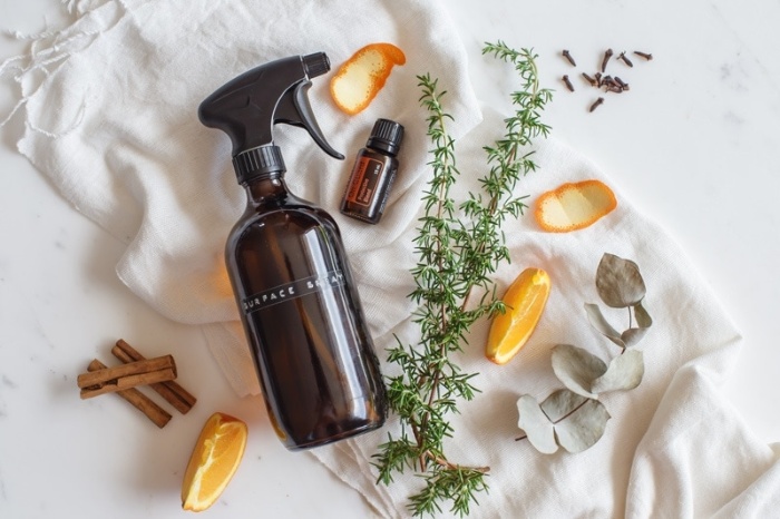 all purpose cleaner in a glass spray bottle with pieces of cinnamon orange slices and herbs