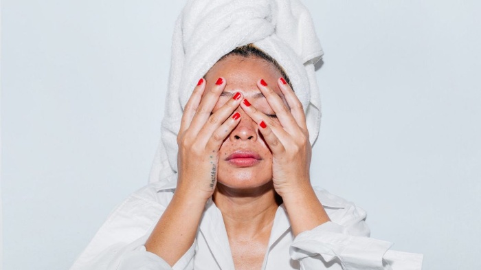 clean your skin woman with a white towel on her head holding her face with two hands