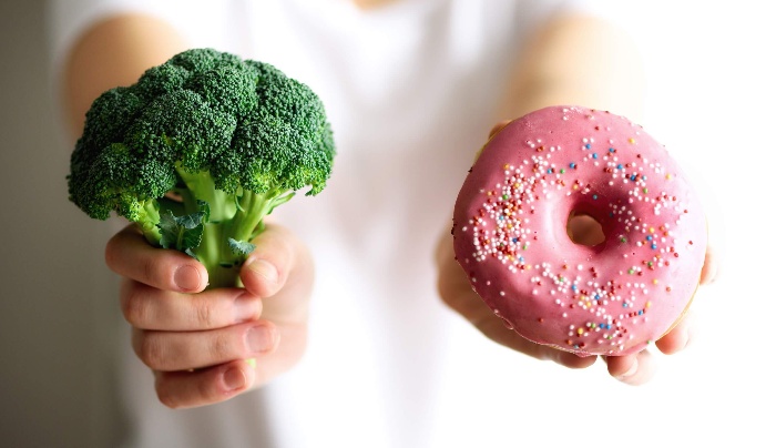 person holding broccoli and donut 