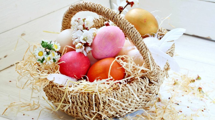 easter basket full of colorful eggs and blossoming spring branches