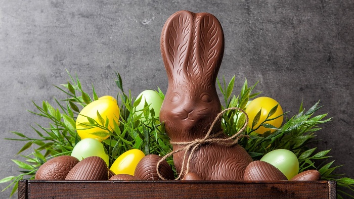 easter chocolate bunny and eggs in a colorful arrangement with green leaves