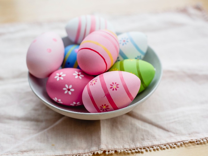 colorful easter eggs in a white bowl on a table with a cloth