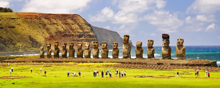 easter islands stone statues on the ocean coast with tourists looking at them