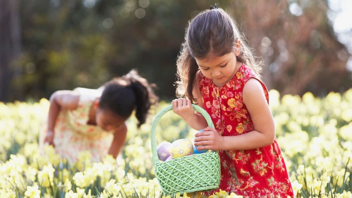 two girls with baskets in a field of flowers searching for easter eggs