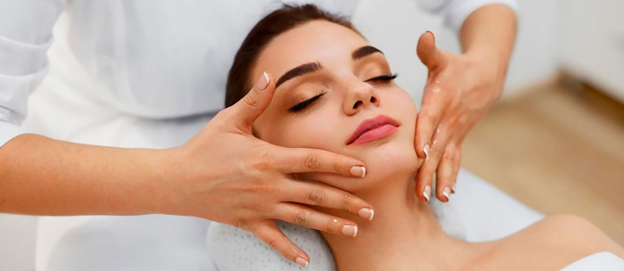 woman getting a facial massage at a salon closing her eyes and enjoying