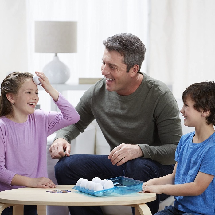 father with two children playing an egg roulette at home 