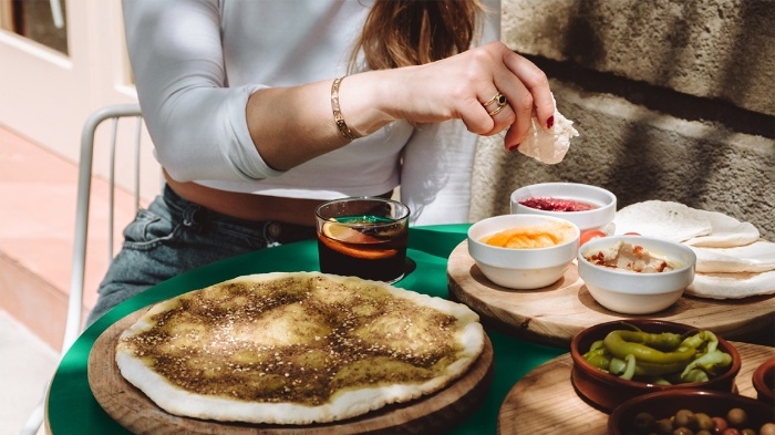 girl eating bread with different dips on a table outdoors