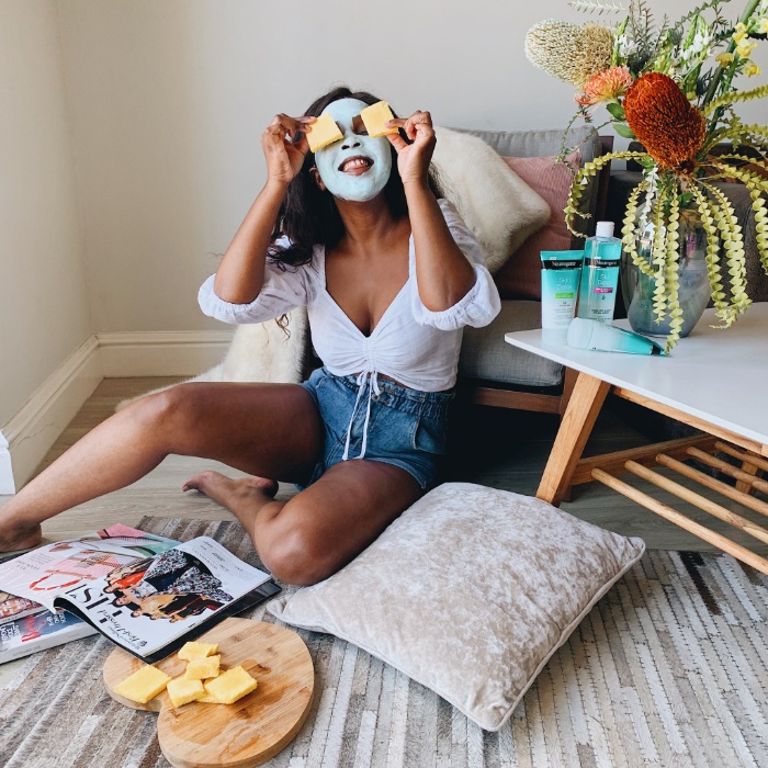 girl skin care girl sitting on the floor with a blue mask on putting pieces of fruit on her eyes 