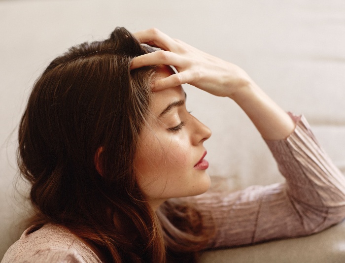 woman in a sofa doing head massage with her hand