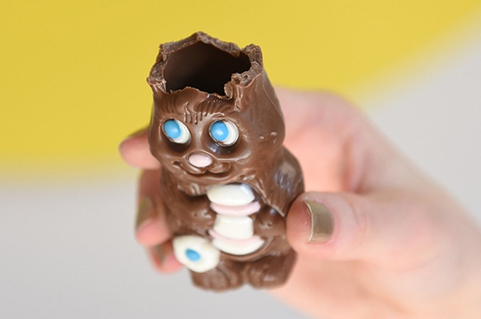 hand holding a hollow easter chocolate bunny missing his ears 