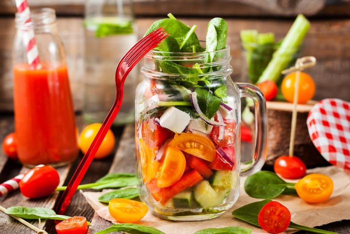 meal in a glass salad with tomatoes greens and other vegetables in a glass