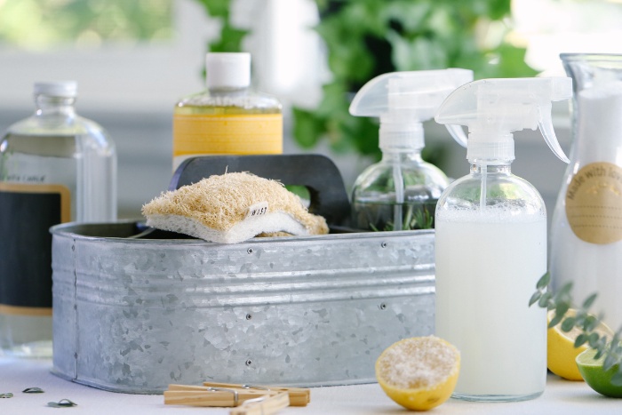 natural cleaners sprays and bottles and a tin with cleaning supplies 