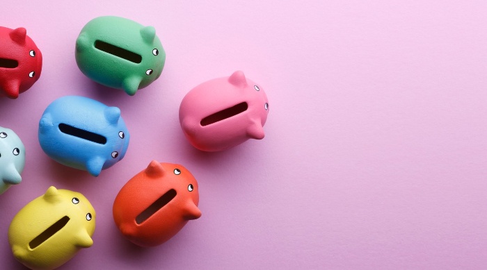 small colorful piggy banks on a pink background