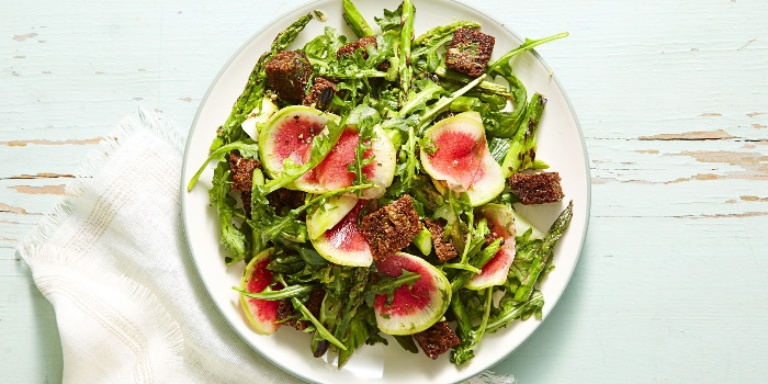 vegan menu green salad with rucola and pieces of fruit on a white table