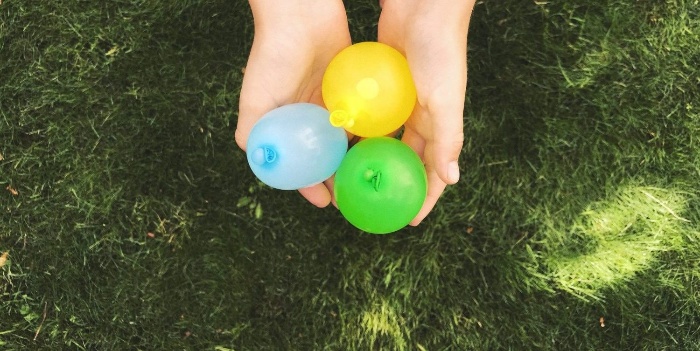 child holding colorful water balloons for an outdoor egg toss game