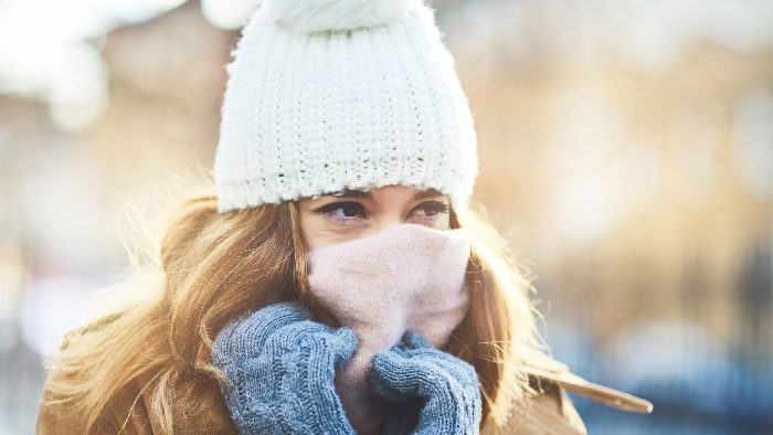 blond woman with white winter hat gloves mask outside in the cold