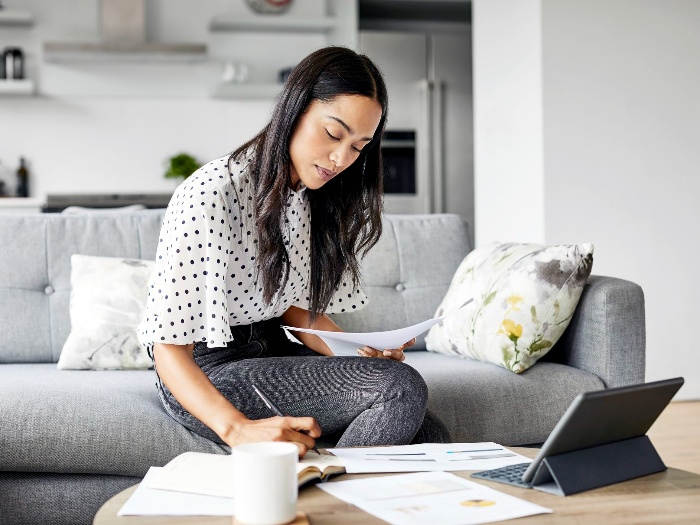 woman bills sitting on the sofa at home calculating bills and writing down