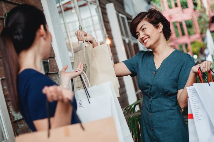 two women shopping and smiling holding shopping bags in their hands