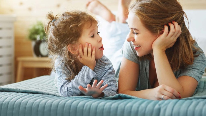 mother and child lying in bed speaking to each other