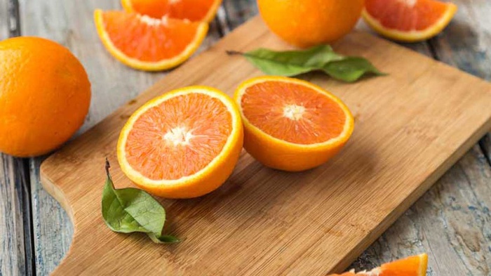 orange in halves and slices on a wooden cutting board