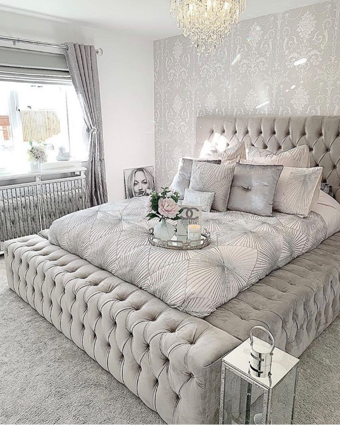 luxury upholstered light gray bed with lots of pillows chandelier light gray bedroom