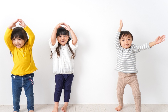 three little children dancing at home and smiling