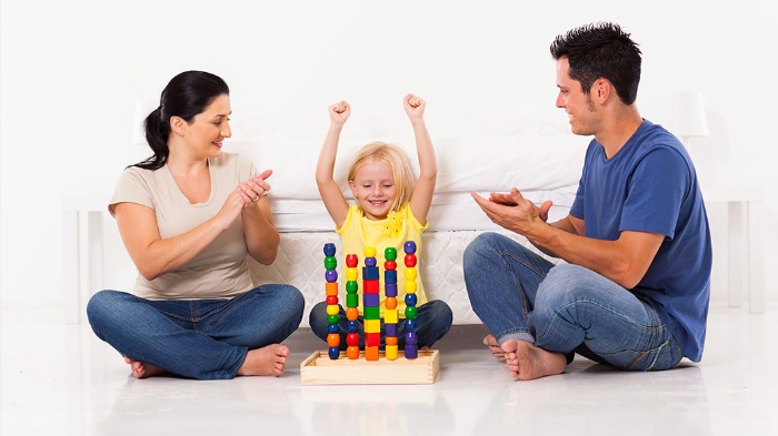 praise kids parents clapping at their child for successfuly arranging colorful toys