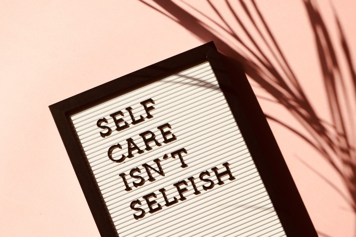 self care isn't selfish writing on a table on a pink table