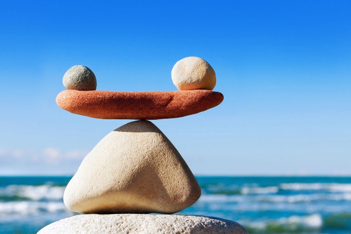 work life balance stones balancing on a beach with the sea in the background