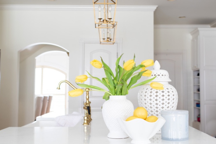 clean white kitchen interior with pop of color yellow tulips and lemons
