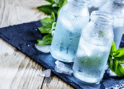 Very cold mineral water with ice in a misted glass bottles, dark background, selective focus