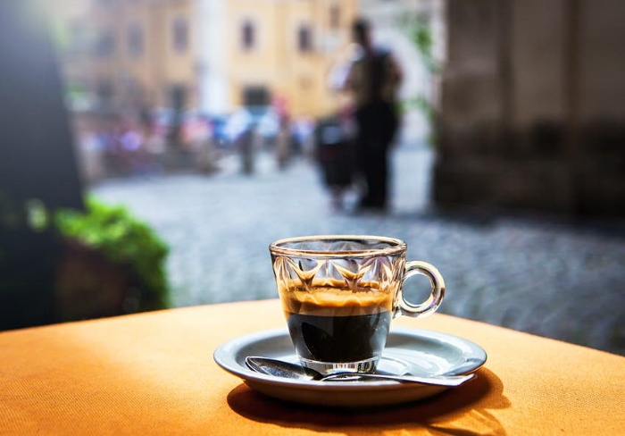 Italian espresso coffee in a glass cup on a table outdoors on the street