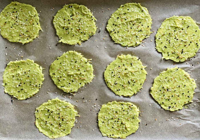 avocado chips on a piece of parchment paper with sesame and other seeds