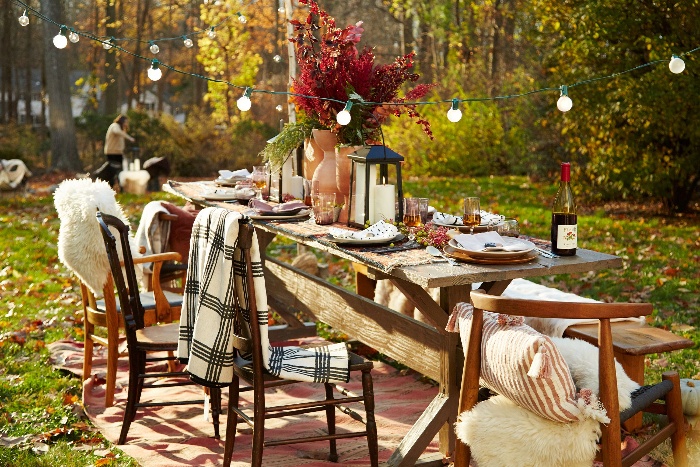 backyard decorating party table with hanging lights and chairs with blankets