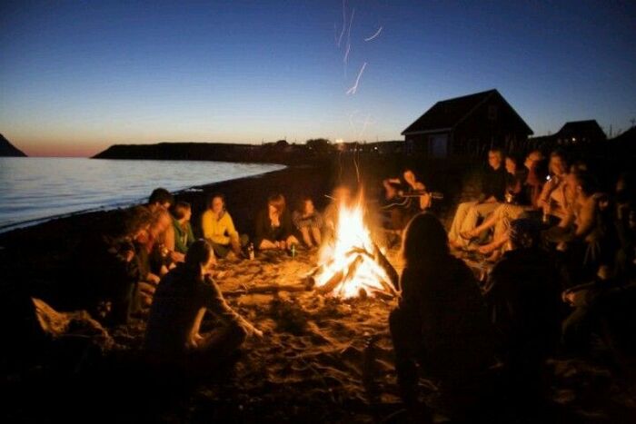 Beach bonfire friends sitting around a fire on the beach talking