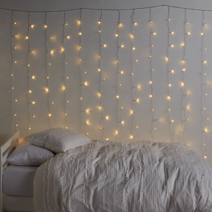 fairy lights on a grey wall over a bed