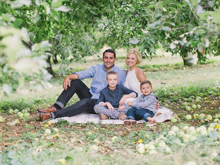 family orchard picnic family of four sitting on the ground under the apple trees