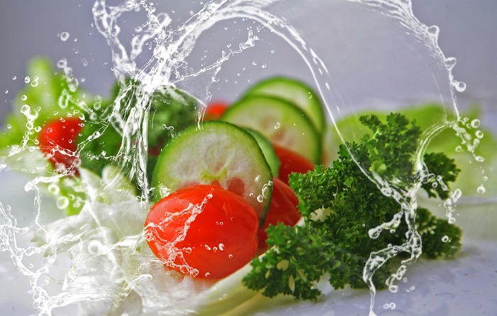 water and vegetables in the background cucumber tomatoes parsley 