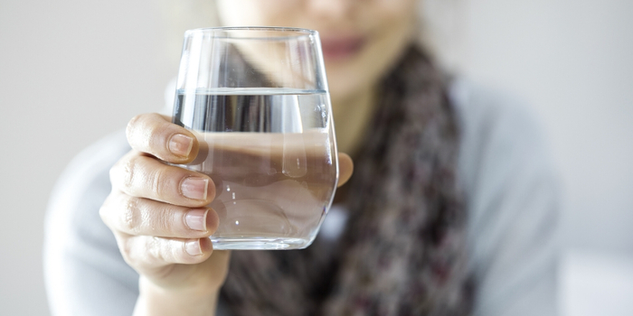 woman dressed in a blouse and a scarf holding a glass of water 