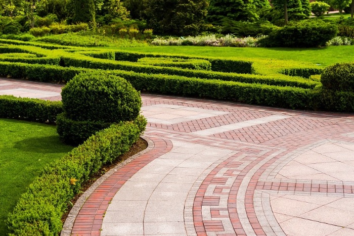 paver walkway with red and beige tiles surrounded by greenery