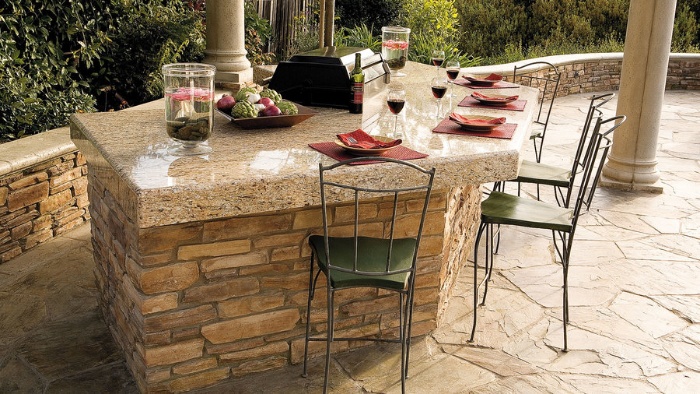 outdoor bar with stone top and iron chairs set for dining